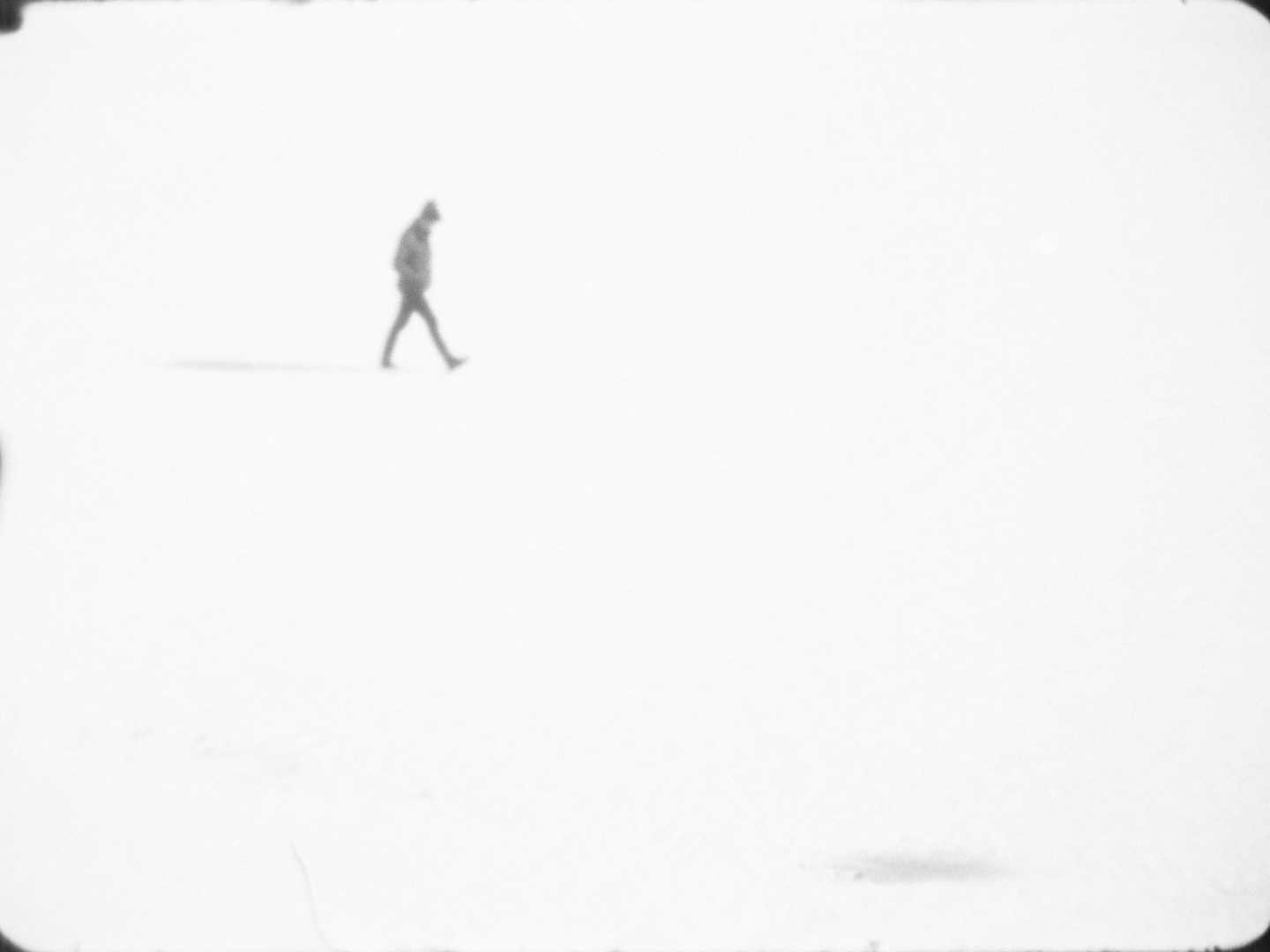 Man walking across snowy field.