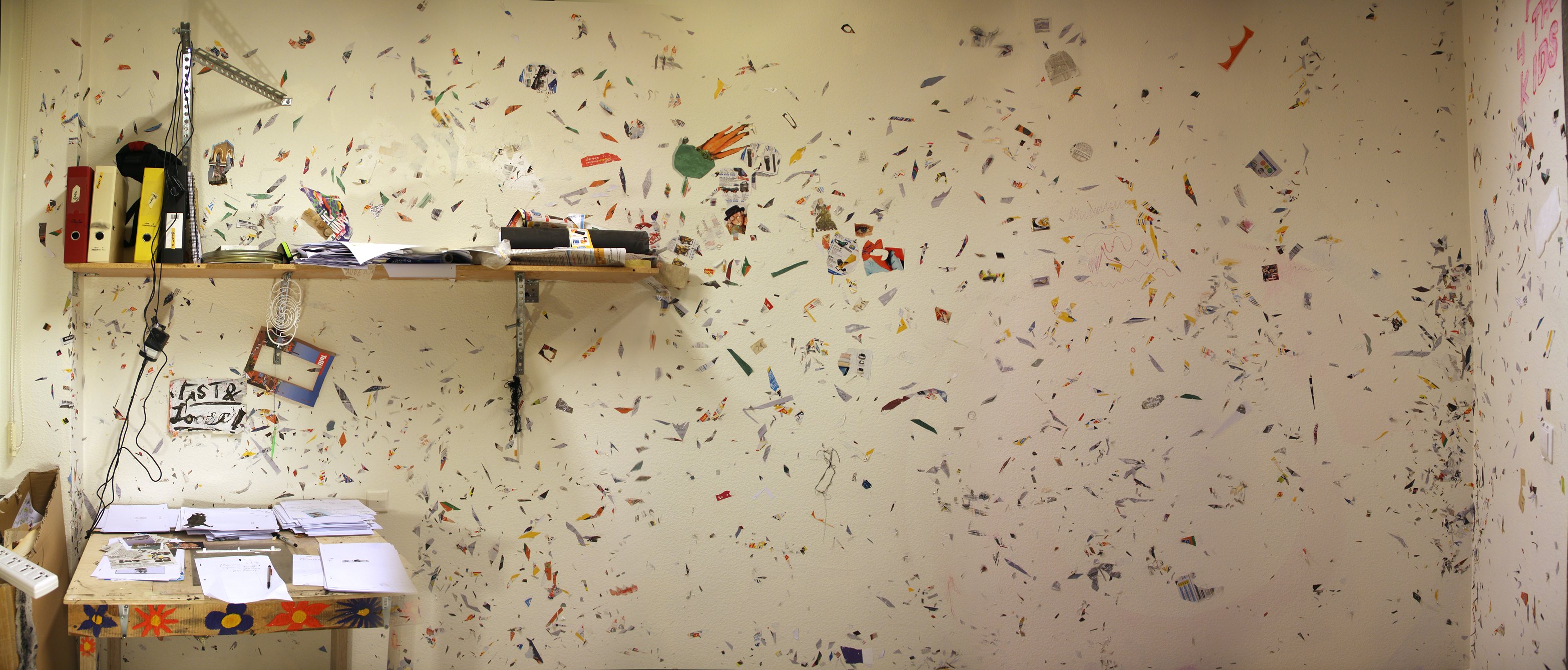 Messy studio with paper cutouts covering wall